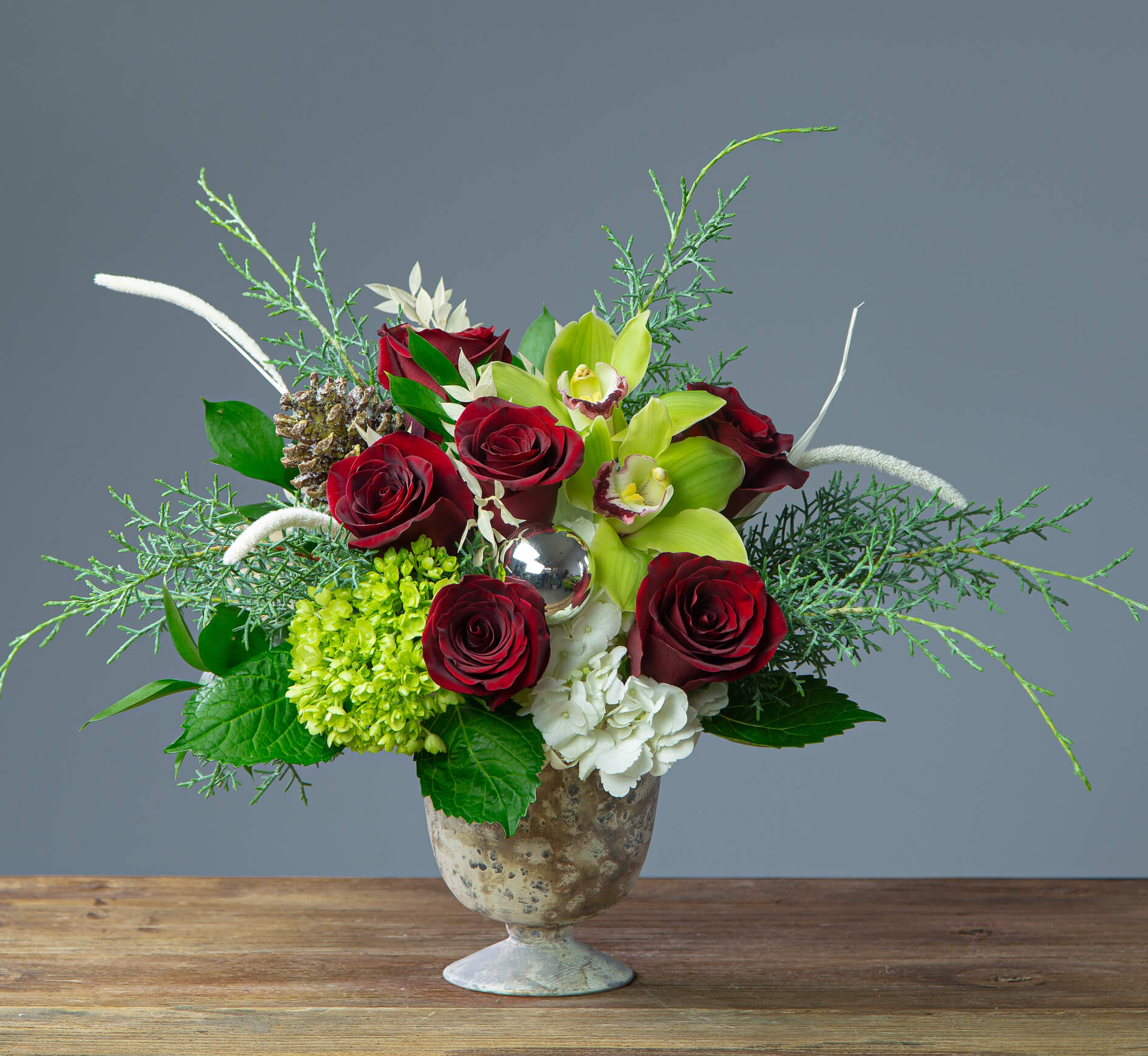 Beautiful flower arrangement in a pedestal vase with red roses and cambium orchids and hydrangeas